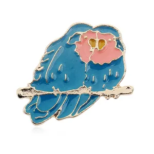 Detalle del broche de búho en esmalte azul y rosa con acabado en metal dorado