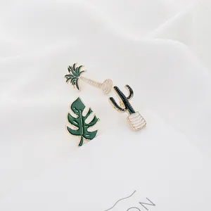 Macro view of tropical enamel pins featuring palm tree, cactus and monstera leaf motifs