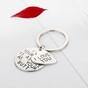Macro shot of silver metal keychain with round and heart charms on a white surface