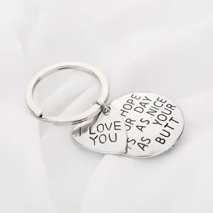 Detail of silver heart and round tags keychain with funny engraved message on silk