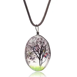 Détail macro du pendentif ovale en résine avec fleurs séchées roses et cordon marron