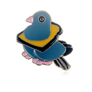 Detalle de un broche de paloma en esmalte con detalles en azul marino y dorado sobre blanco