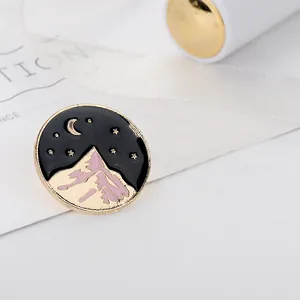Broche ronde en émail avec montagnes dorées sous un ciel étoilé et croissant de lune