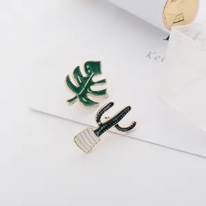 Detail of tropical monstera leaf and cactus enamel pins with elegant gold plating