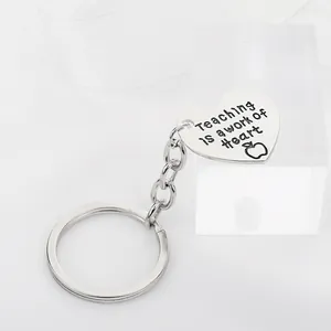 Silver heart keychain with Teaching is a work of Heart engraving and apple icon detail
