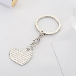 Silver metal heart-shaped keychain with textured surface on a white background