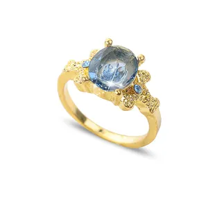 Bague vintage en or avec gemme bleue ovale et anneau texturé sur fond blanc
