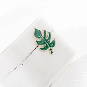 Exquisite green Monstera leaf brooch with gold metallic edges on white display base