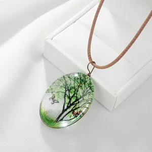 Vue détaillée du pendentif ovale avec arbre vert et motifs de papillons colorés
