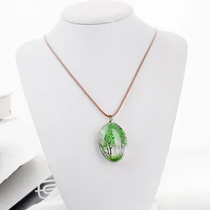 Gros plan détaillé du pendentif ovale en verre avec fleurs séchées vertes et cordon
