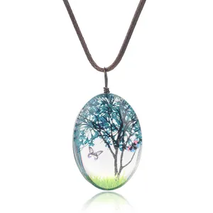 Pendentif ovale en résine avec fleurs séchées et motif papillon sur un cordon tressé