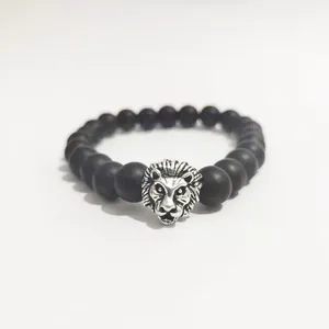 Detalle de cuentas negras mates y dije de cabeza de león plateada en esta pulsera de hombre