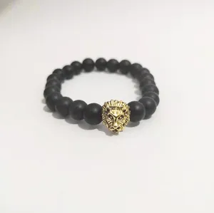 Detalle de pulsera de cuentas negras mate con adorno de cabeza de león dorada