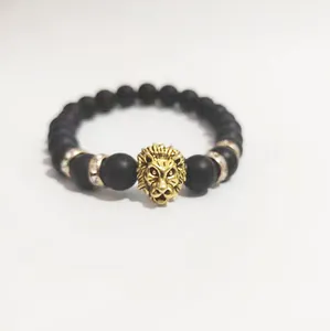Detalle de pulsera de cabeza de león con cuentas negras mate y adornos metálicos dorados