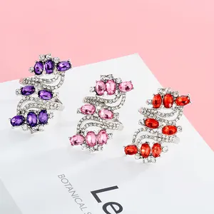 Detailed close-up of S-shaped silver rings with purple, pink and red crystals