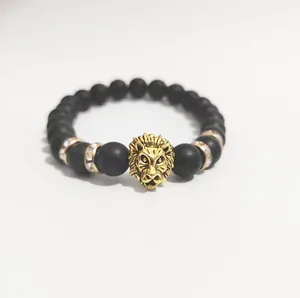 Detalle de pulsera de cuentas negras mate con cabeza de león dorada y cristales