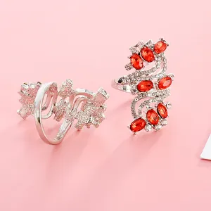 Detailed view of silver S-shape ring with red oval gemstones and sparkling rhinestones