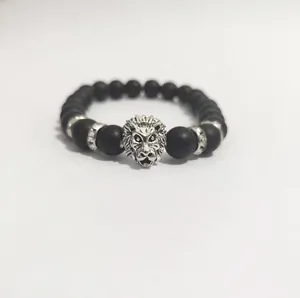 Detalle de la pulsera de cuentas negras mate con dije de cabeza de león plateado y strass