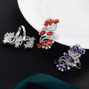 Close-up of S-shaped silver-tone rings with vibrant red and purple crystals and pavé diamonds