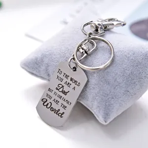 Steel DAD dog tag keychain with family message on a gray velvet pillow display