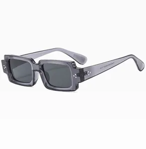 Detail view of transparent grey rectangular sunglasses with silver rivets and serial code