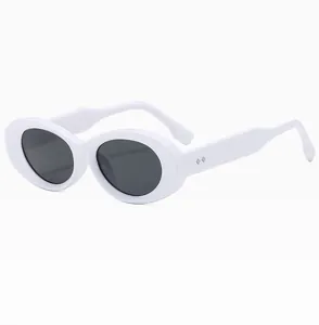 Close-up of white oval frame sunglasses with black lenses and diamond metal rivets