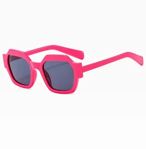 Detail view of bold neon pink polygonal sunglasses with dark grey lenses and thick frames