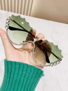 Close-up of rimless wave-edge sunglasses with light green gradient lenses and rhinestones