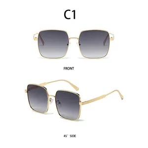 Detail view of large square metal sunglasses with gold diamond-patterned temples and grey lenses