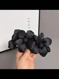 Detailed view of handmade black satin fabric large floral hair clip with silk texture
