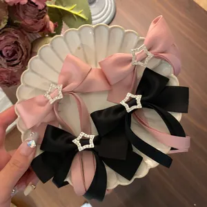 Elegante Haarspangen mit Satin-Schleifen in Rosa und Schwarz sowie Strass-Stern-Anhängern