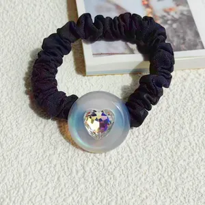Detail of black pleated scrunchie with iridescent pearl button and heart crystal