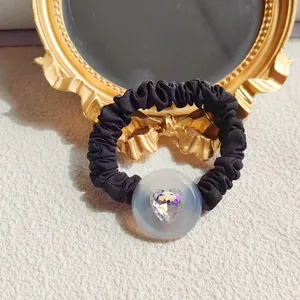 Elegant black pleated scrunchie with a sparkling heart-shaped crystal on white plush fur
