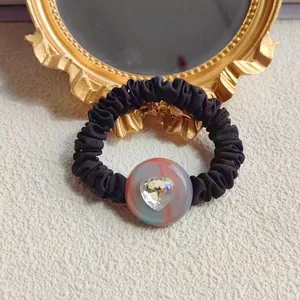 Elegant black scrunchie with a pink marble heart crystal on a vintage gold frame