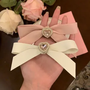 Cremefarbene Haarschleifen mit Herz-Strass und Perlen in einem sanften Blumen-Dekor