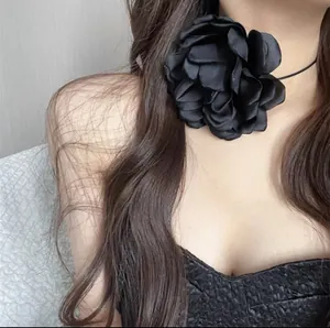 Elegante girocollo con rosa in tessuto nero e cordino sottile indossato da una modella
