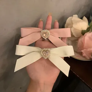 Rosa und cremefarbene Schleifen-Haarspangen mit Herz-Strasssteinen und Perlen