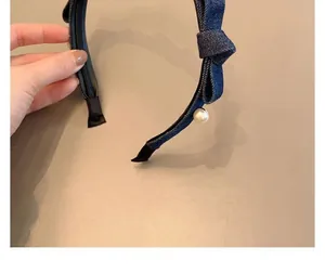 Detail of blue denim headband with bow and pearl featuring black non-slip lining