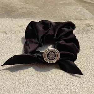 Elegant black satin scrunchie with a vintage bow and crystal-rimmed rose metal center