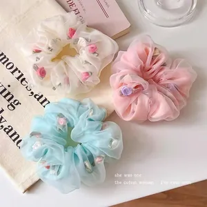 Detail of floral chiffon scrunchies with fabric roses in cream pink and blue colors