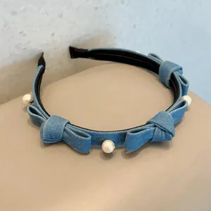 Light blue denim headband with bow accents and white pearls on a minimalist background
