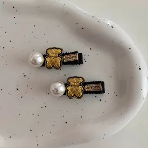 Cute vintage gold bear hair clips with pearls and Lovedays metal plate on white ceramic