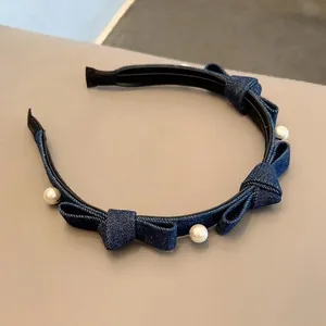 Blue denim headband with bow knots and faux pearls on light beige background