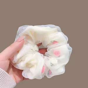Detail of off-white mesh scrunchie with pink floral inserts and pleated texture