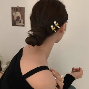 Set of two gold bear and pearl hair clips for women shown on a model's elegant hairstyle