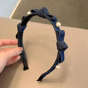 Blue denim headband with handmade 3D bows and pearls shown in a hand-held display