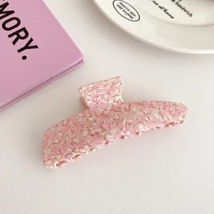 Close-up of pink marble texture acetate hair claw clip with cream marble accents