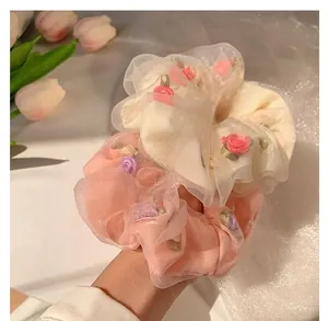 Detail of mesh scrunchies with 3D flower embroidery in beige and light pink colors