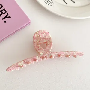 Detailed shot of pink marble texture acetate hair claw clip on white leather background