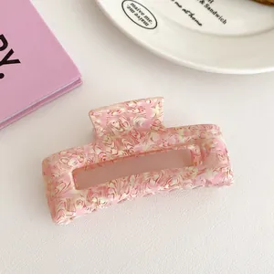 Detail of pink marble textured acetate hair claw clip on a minimalist aesthetic background